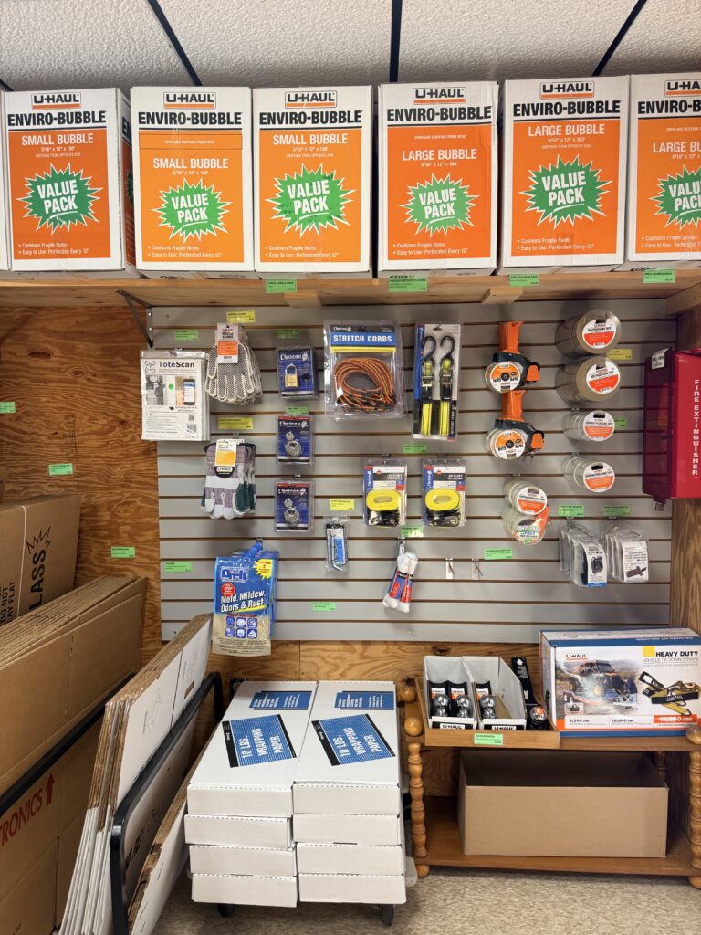 U-Haul packing supplies display featuring bubble wrap boxes, storage containers, and various moving accessories like gloves, cords, and tape.